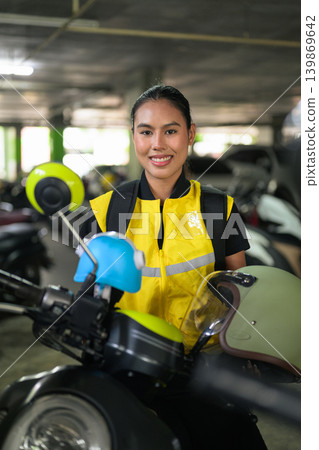 Vertical Portrait of Smiling Female Delivery Courier on Scooter in Garage Vertical Portrait of Smiling Female Delivery Courier on Scooter in Garage 139869642