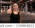 Smiling Female Athlete Giving Thumbs Up in Gym 139869822