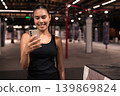 Smiling Female Athlete Using Smartphone Inside Gym 139869824