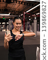 Smiling Female Athlete Syncing Smartphone and Smartwatch in Vertical Shot 139869827