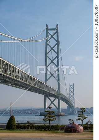 View of the main towers of the Akashi Kaikyo Bridge and the park from the Awaji roadside station. 139870087