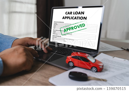 Businessman reviewing approved car loan application on laptop with vehicle model and car key on desk for auto financing, banking approval, credit assessment, and vehicle purchase process. Businessman reviewing approved car loan application on laptop with vehicle model and car key on desk for auto financing, banking approval, credit assessment, and vehicle purchase process. 139870515