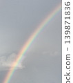 A vivid rainbow stretches clearly across the cloudy sky after the rain. 139871836