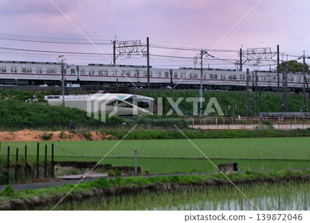A scene of JR East's resort train, Shiki-shima, and Tobu Isesaki Line commuter trains crossing paths in a rice paddy area. A scene of JR East's resort train, Shiki-shima, and Tobu Isesaki Line commuter trains crossing paths in a rice paddy area. 139872046