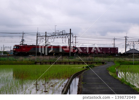 A freight train running through rice paddies. A freight train running through rice paddies. 139872049