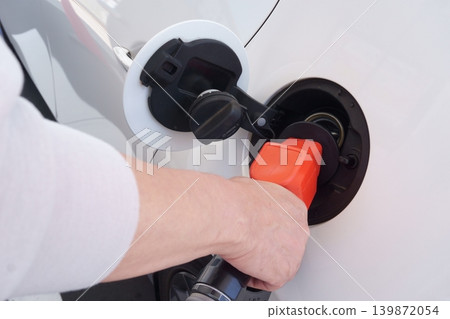 The hands of a person refueling at a gas station The hands of a person refueling at a gas station 139872054