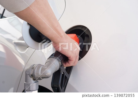 The hands of a man filling up his car with gasoline at a gas station. The hands of a man filling up his car with gasoline at a gas station. 139872055