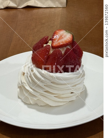 Pavlova dessert topped with fresh strawberries on a white plate, perfect for a food background Pavlova dessert topped with fresh strawberries on a white plate, perfect for a food background 139872560