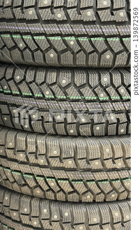 Stacked winter car tires with visible studded treads, suitable for automotive use background Stacked winter car tires with visible studded treads, suitable for automotive use background 139872569