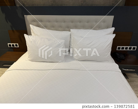 Cozy hotel bed with soft white pillows and sheets, offering a comfortable and inviting atmosphere Cozy hotel bed with soft white pillows and sheets, offering a comfortable and inviting atmosphere 139872581