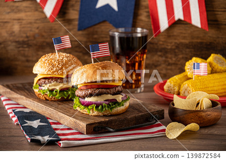 Cheeseburgers with American flags and barbecue party decorations for Fourth of July Cheeseburgers with American flags and barbecue party decorations for Fourth of July 139872584