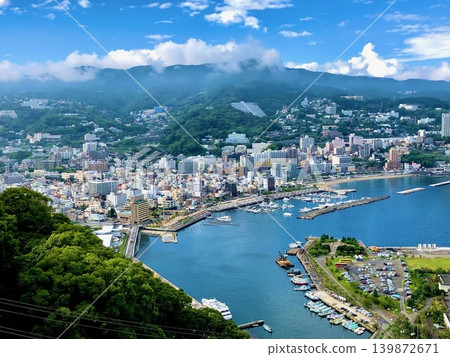 熱海景色令人嘆為觀止:碧藍的相模灣在鬱鬱蔥蔥的綠樹和起伏的山脈間盡收眼底。 熱海景色令人嘆為觀止:碧藍的相模灣在鬱鬱蔥蔥的綠樹和起伏的山脈間盡收眼底。 139872671