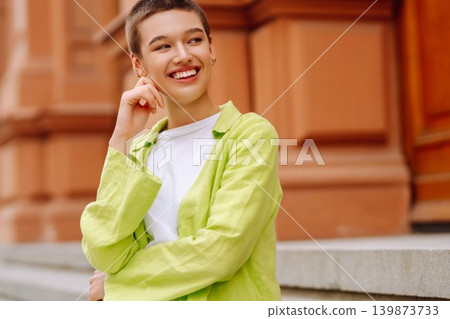 Stylish young woman with short haircut posing on city streets. The concept of fashion, style. Stylish young woman with short haircut posing on city streets. The concept of fashion, style. 139873733