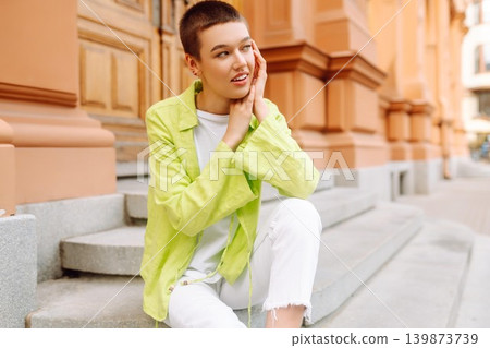 Stylish young woman with short haircut posing on city streets. The concept of fashion, style. Stylish young woman with short haircut posing on city streets. The concept of fashion, style. 139873739