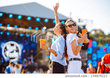 Two woman having great time at music festival. Girlfriends rinking beer at Beach party. Lifestyle. 139874121