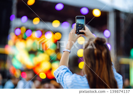 Holding a mobile phone in hands and shooting photo or video content. Youth, party, vacation concept. Holding a mobile phone in hands and shooting photo or video content. Youth, party, vacation concept. 139874137