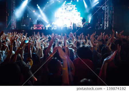 Crowd at concert - Cheering crowd in front of bright colorful stage lights Crowd at concert - Cheering crowd in front of bright colorful stage lights 139874192