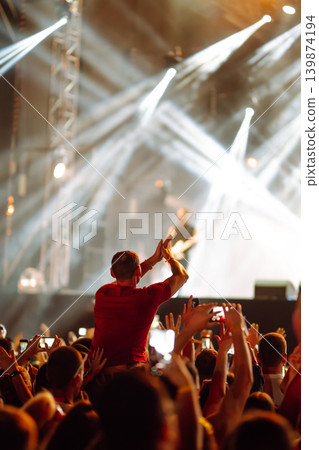 Crowd at concert - Cheering crowd in front of bright colorful stage lights Crowd at concert - Cheering crowd in front of bright colorful stage lights 139874194