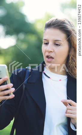 Woman with curly hair talking on smartphone on the street. Close-up. Communication technologies and modern lifestyle concept. Woman with curly hair talking on smartphone on the street. Close-up. Communication technologies and modern lifestyle concept. 139874452