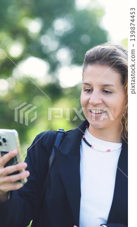 Woman with curly hair talking on smartphone on the street. Close-up. Communication technologies and modern lifestyle concept. Woman with curly hair talking on smartphone on the street. Close-up. Communication technologies and modern lifestyle concept. 139874453