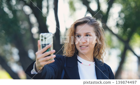 Woman with curly hair talking on smartphone on the street. Close-up. Communication technologies and modern lifestyle concept. Woman with curly hair talking on smartphone on the street. Close-up. Communication technologies and modern lifestyle concept. 139874497