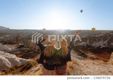 Hot air balloon flying over spectacular Cappadocia - girls watching of Cappadocia. Travel concept. 139874726