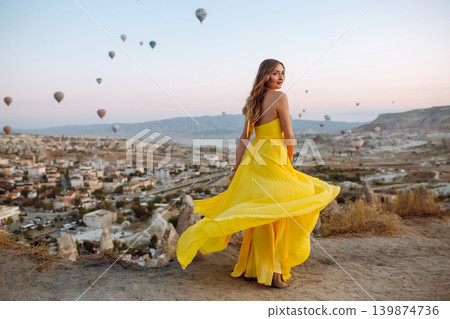 Woman stands on mountain with flying air balloons on background. Tourist Turkish region Cappadocia. 139874736