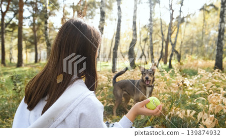 Young woman walking with a dog in an autumn forest Young woman walking with a dog in an autumn forest 139874932