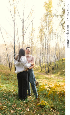 Married couple relaxing in nature during a walk in the autumn forest. Woman and man in love walking through tall yellow grass, in fern leaves Married couple relaxing in nature during a walk in the autumn forest. Woman and man in love walking through tall yellow grass, in fern leaves 139875029