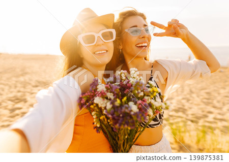 Two pretty friends women making selfie on beach, light and bright summer colors. Friends together 139875381