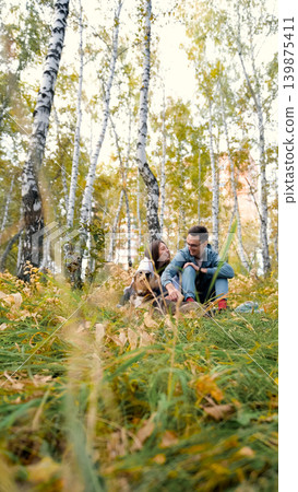 A woman and a man in love are walking in an autumn forest, in tall yellow grass, in fern leaves, a dog is walking next to them. A married couple is relaxing in nature during a walk with their beloved A woman and a man in love are walking in an autumn forest, in tall yellow grass, in fern leaves, a dog is walking next to them. A married couple is relaxing in nature during a walk with their beloved 139875411