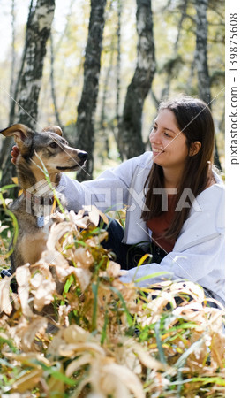 Young woman walking with a dog in an autumn forest Young woman walking with a dog in an autumn forest 139875608