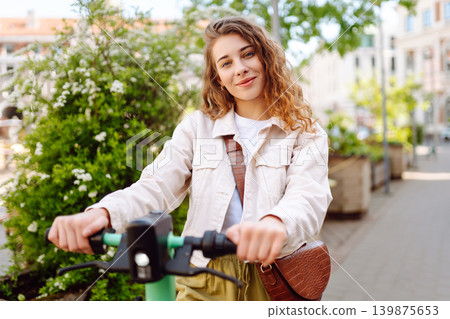 Happy woman rides electric scooter at weekend leisure time. Ecological transport. Active lifestyle. 139875653