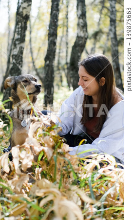 Young woman walking with a dog in an autumn forest Young woman walking with a dog in an autumn forest 139875663
