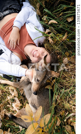 Young woman relaxes while walking her dog in autumn forest 139875671