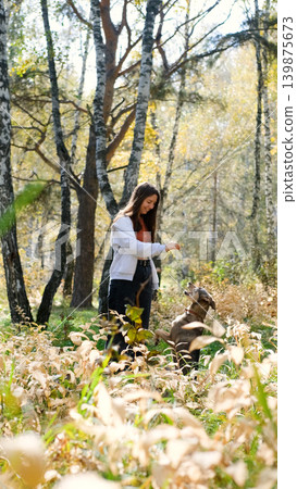 Young woman walking with a dog in an autumn forest Young woman walking with a dog in an autumn forest 139875673