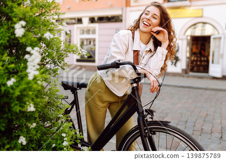 Lovely young woman posing with bike on street of city, on sunny day. Active lifestyle. Eco transport Lovely young woman posing with bike on street of city, on sunny day. Active lifestyle. Eco transport 139875789
