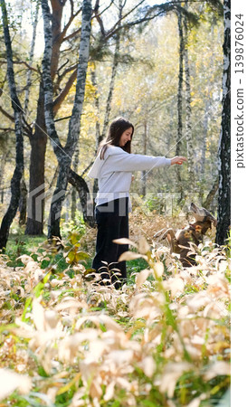 Young woman walking with a dog in an autumn forest Young woman walking with a dog in an autumn forest 139876024