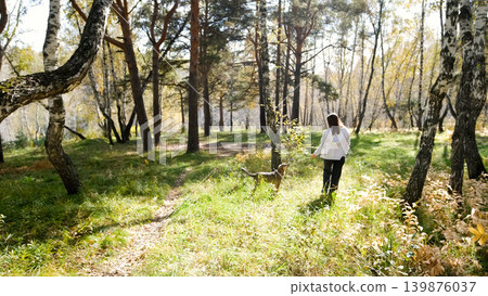 Young woman walking with a dog in an autumn forest Young woman walking with a dog in an autumn forest 139876037