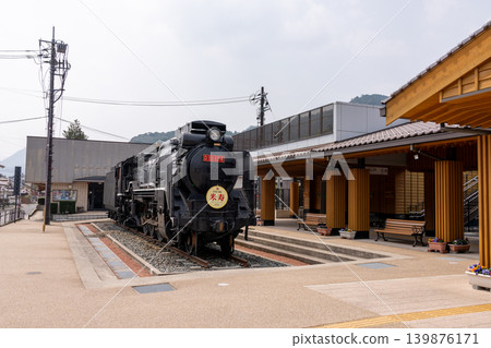 A historical steam locomotive on display at a traditional Japanese railway station. A historical steam locomotive on display at a traditional Japanese railway station. 139876171