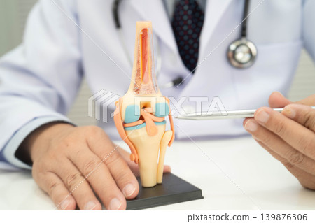 Asian doctor holding spinal nerve and bone model, Lumbar spine displaced herniated disc fragment for treatment medical in the orthopedic department. 139876306