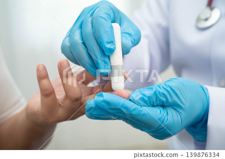 Doctor check diabetes from finger blood sugar level with finger lancet. Doctor check diabetes from finger blood sugar level with finger lancet. 139876334