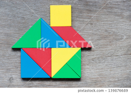 Color wooden puzzle in house or home shape on wood background Color wooden puzzle in house or home shape on wood background 139876689