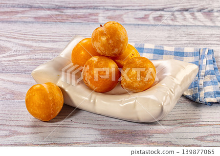 Fresh yellow plums in white ceramic dish on rustic wooden table with napkin Fresh yellow plums in white ceramic dish on rustic wooden table with napkin 139877065