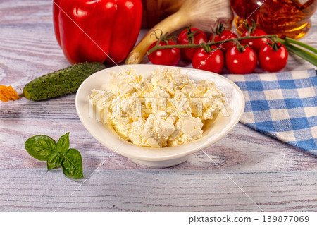 Fresh cottage cheese in bowl with assorted vegetables like tomatoes, pepper, and cucumber on rustic wooden table. Healthy eating concept Fresh cottage cheese in bowl with assorted vegetables like tomatoes, pepper, and cucumber on rustic wooden table. Healthy eating concept 139877069