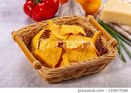 Tortilla chips in wicker basket with fresh vegetables and cheese for snacking Tortilla chips in wicker basket with fresh vegetables and cheese for snacking 139877086