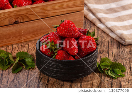 Ripe red strawberries in black bowl and wooden crate on rustic table Ripe red strawberries in black bowl and wooden crate on rustic table 139877096