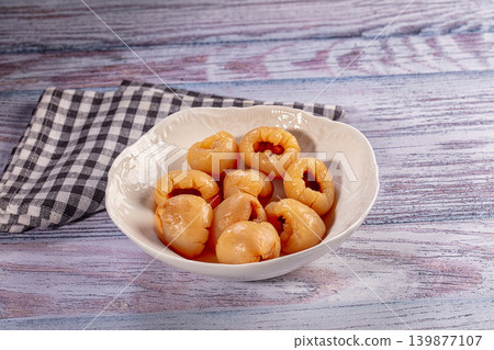 Pitted longan fruit in white ceramic bowl on colorful rustic wood table with napkin Pitted longan fruit in white ceramic bowl on colorful rustic wood table with napkin 139877107