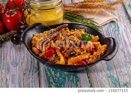 Couscous with meat and vegetables in black bowl on rustic wooden table Couscous with meat and vegetables in black bowl on rustic wooden table 139877115