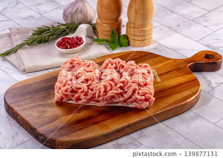 Raw minced chicken or turkey meat on wooden cutting board with fresh herbs and spices for cooking Raw minced chicken or turkey meat on wooden cutting board with fresh herbs and spices for cooking 139877131